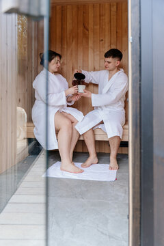 Young White Couple Sharing Tea Inside Wooden Sauna