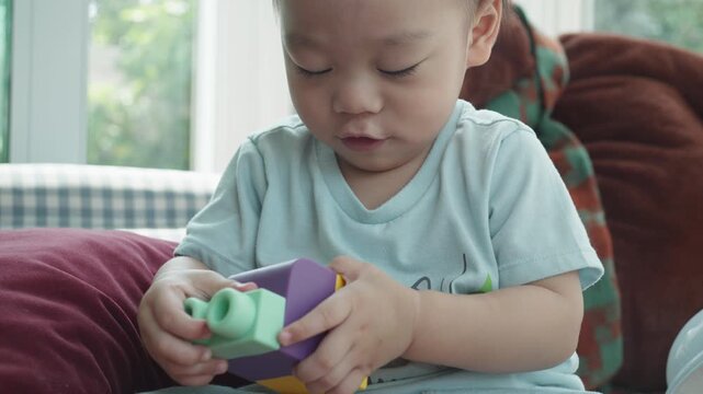 A young child focuses intently while playing with colorful building blocks. This joyful moment captures the essence of early childhood creativity and learning through play, promoting development and i