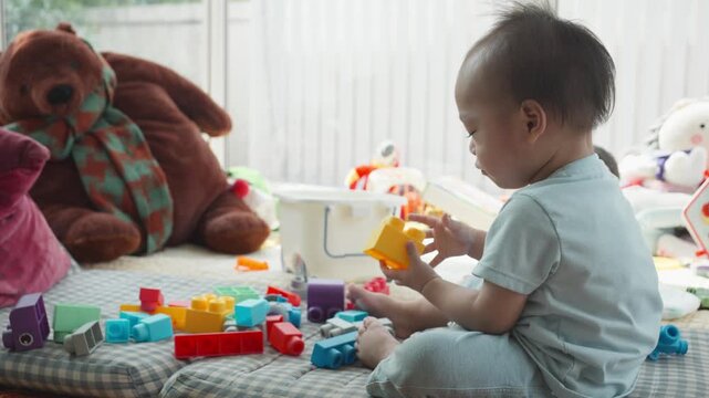 A young child is engaged in play with bright building blocks and toys on a soft surface. This playful scene captures the joy and creativity of early childhood, emphasizing the importance of play in de