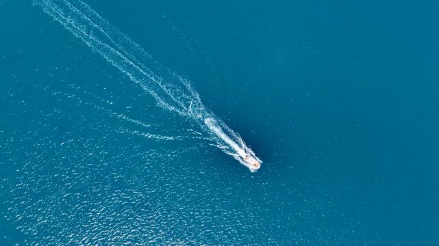 A shot taken at a right angle of a speedboat gliding through Adrasan&rsquo;s enchanting turquoise waters, leaving trails of white foam in its wake.