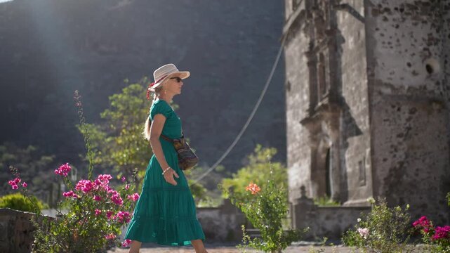 A happy senior woman walks through the garden of San Javier Mission as the sun rises in Baja California Sur, Mexico