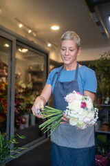 Fototapeta premium Female florist arranging cut flowers for retail display