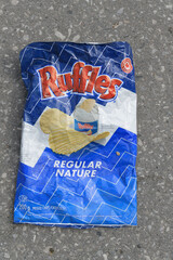 Naklejka premium discarded bag of Ruffles regular potato chip on asphalt pavement, Toronto