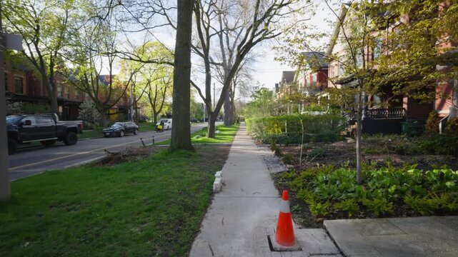 First person perspective walking along a sidewalk in a peaceful residential neighborhood, revealing typical North American suburban houses