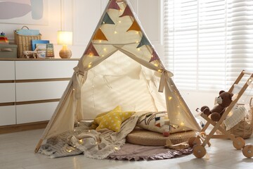 Cute wigwam with fairy lights and toys in stylish child's room © New Africa