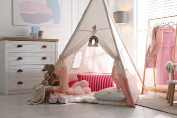 Cute wigwam, clothes, cushions and toy in stylish child's room © New Africa