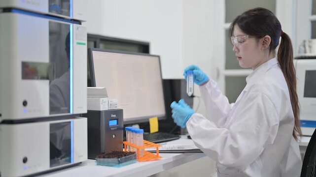 Scientist in lab coat and gloves conducts experiment with test tubes and equipment