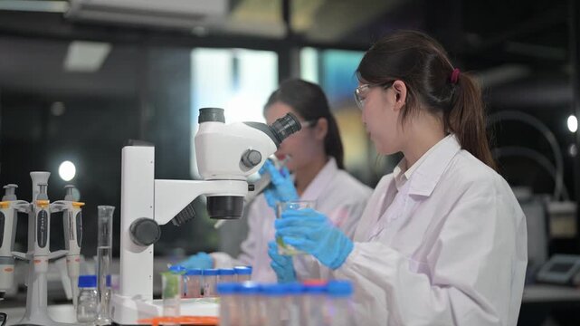 Young scientists in protective gear conduct experiments with microscopes and pipettes