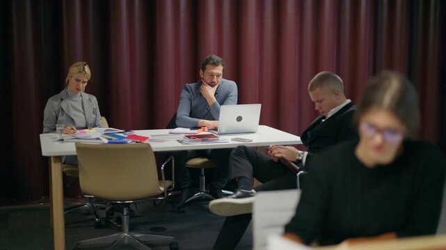 Employees collaborate efficiently during a productive business meeting in an office setting. Colleagues are diligently working together on various projects