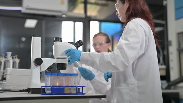 Scientists in lab coats and safety glasses conduct experiments with test tubes and microscopes