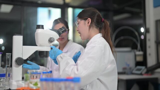 Scientists in lab coats collaborating and examining samples under a microscope
