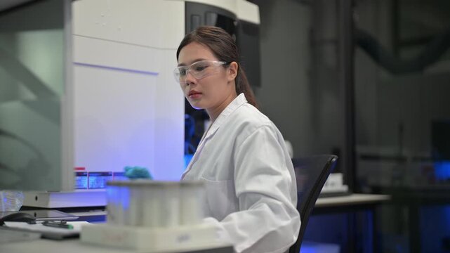 Scientist in protective gear meticulously works with samples and computer in modern laboratory
