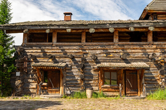 The impressive wooden walls of a reconstructed Old Slavic fortress, made of round, hewn logs. Old barracks and boyar chambers. A bright, sunny day.