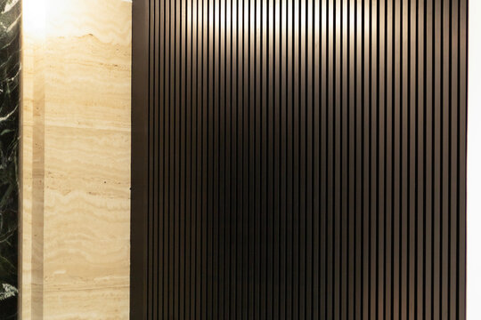 Dark vertical wooden slats wall texture with beige travertine stone panel