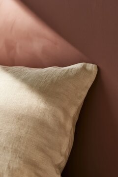 Cream linen pillow on burgundy velvet background. textural contrast, neutral accent, luxurious bedding detail.