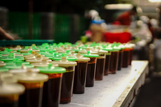 Rows of pre-poured sweet iced tea and herbal drinks in glasses at an Indonesian street food market.