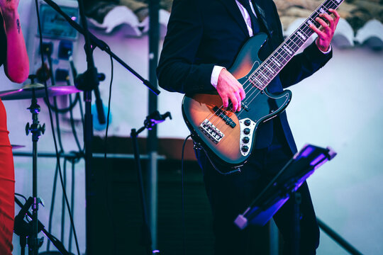 Bass guitarist performing live on stage, creating music in a band setting