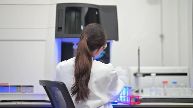 Scientist in lab coat and gloves performs experiment with test tubes and equipment