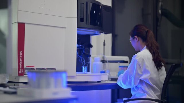 Scientist in lab coat works with advanced analytical instrument and samples