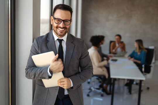 Confident banking professional in modern office holding laptop, symbolizing finance, investment