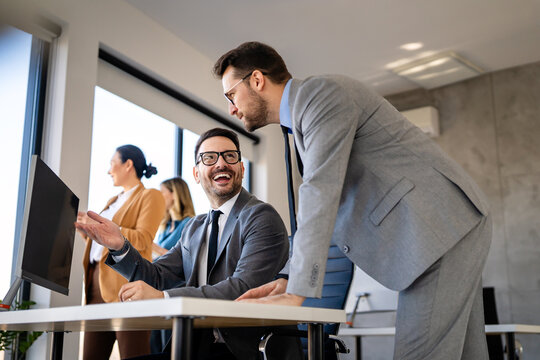 Happy multiethnic businesspeople laughing while collaborating on a new project in an office.