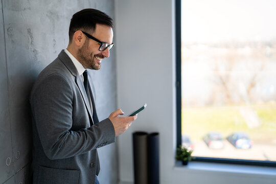 A confident business man leads her busy office life, multitasking with smartphone communication