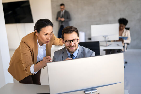 Happy multiethnic businesspeople laughing while collaborating on a new project in an office.