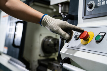 Obraz premium Worker's gloved hand presses the red emergency stop button on industrial machinery