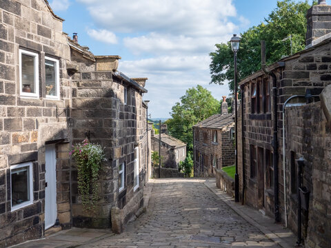 Town gate the main street in the historic village of Heptonstall in summer with the cobbled road surrounded by old stone houses in summer