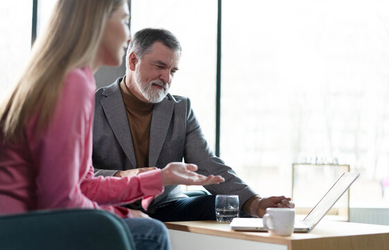 Two business partners checking document working together on laptop computer in office at corporate meeting