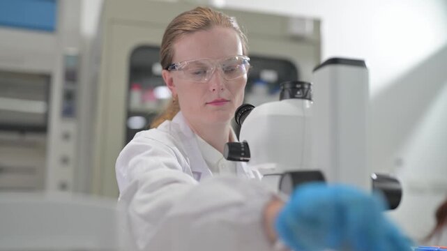 Scientist in protective gear meticulously works with samples under a microscope
