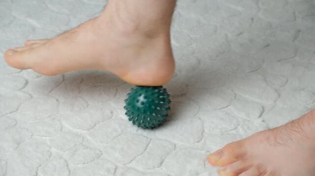 Man massaging myofascial trigger points on foot with green spiky ball