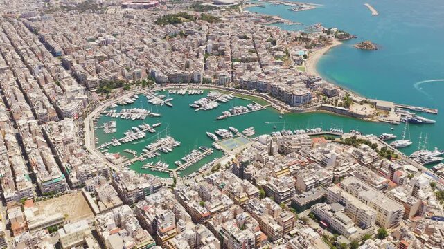 High-altitude aerial view revealing the dense urban landscape of piraeus and the bustling zea marina, a harbor filled with numerous yachts and sailboats on a sunny day in athens, greece