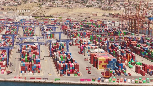 Expansive aerial perspective of a massive industrial shipping port, where gantry cranes and reach stackers organize multicolored cargo containers for global trade and logistics operations