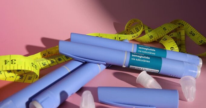 Tracking close to multiple semaglutide glp1 injection devices with sterile pen needles and a yellow measuring tape on pink gradient.
