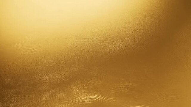 Slow motion close up of gold metallic surface gently rippling and reflecting light on seamless studio set with subtle gradient glossy texture