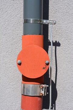 Metal lightning protection system integrated with a downspout pipe and bonding clamp on an exterior wall of a building