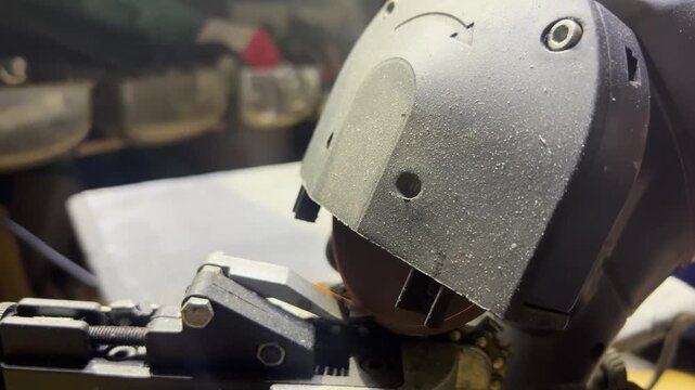 Closeup video of circular saw cutting metal chain with sparks flying. Industrial tool operation in workshop setting