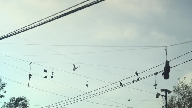 Low angle view of sneakers and boxing gloves hanging from power lines in a Latin American neighborhood street