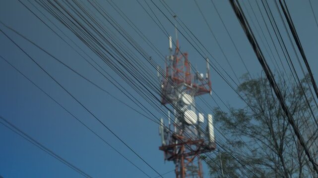 Cell phone tower antenna behind tangled power lines in Latin American urban area