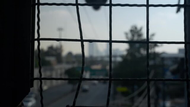 Urban landscape of Mexico City highway and skyscrapers seen through a blurry wire mesh fence
