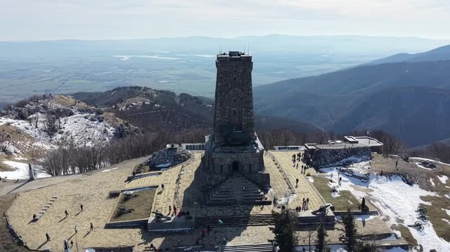 Aerial view of the Shipka Freedom Monument on top of a snowy mountain peak in winter, Bulgaria. Beautiful drone shot of historic balkan landmark.