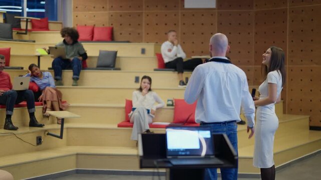 A diverse group of professionals attends a modern workshop presentation in a tiered auditorium. Colleagues engage in an interactive session, learning and sharing ideas