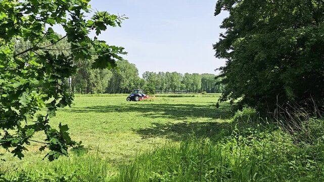 May 22, 2026, Diepenbeek. Tractor mowing grass in rural field under clear sky