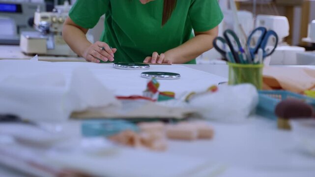 Female designer tracing a pattern on fabric with a pencil in a professional sewing studio