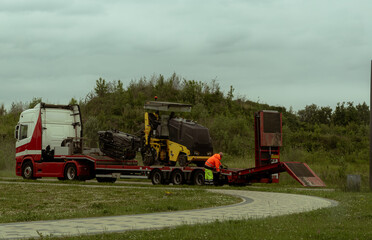 Fototapeta premium Heavy Road Construction Machinery Transported on Trailer in Riga