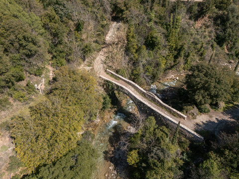 Old stone arched bridge over a neda river in a lush green forest in Greece