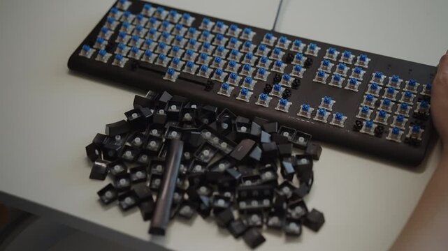 Technician removing keycaps from mechanical keyboard with special tool for cleaning and maintenance, dropping keys into container. Geek culture and electronic device repair concept