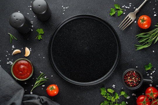 Black empty plate, Fresh herbs, spices and vegetables.