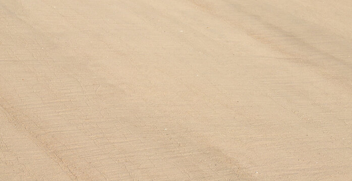 Smooth beige beach sand with soft diagonal lines as clean natural textured background